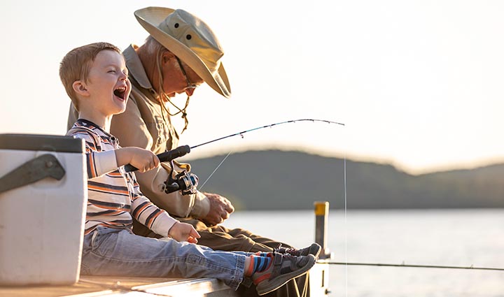 Flexible Premium Deferred Annuity - young boy fishing with his grandad while sitting on a dock.
